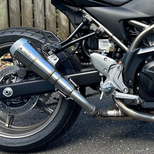 Black motorcycle parked on a street with a wooden fence in the background