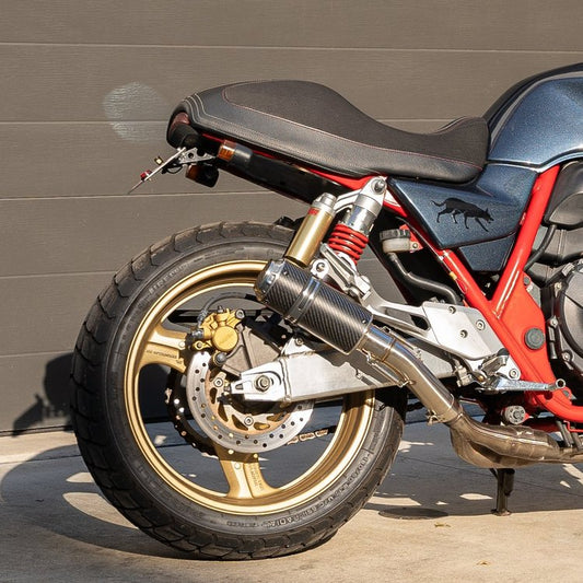 A black and red Honda CB400 motorcycle with a custom slip-on exhaust system parked on the street.