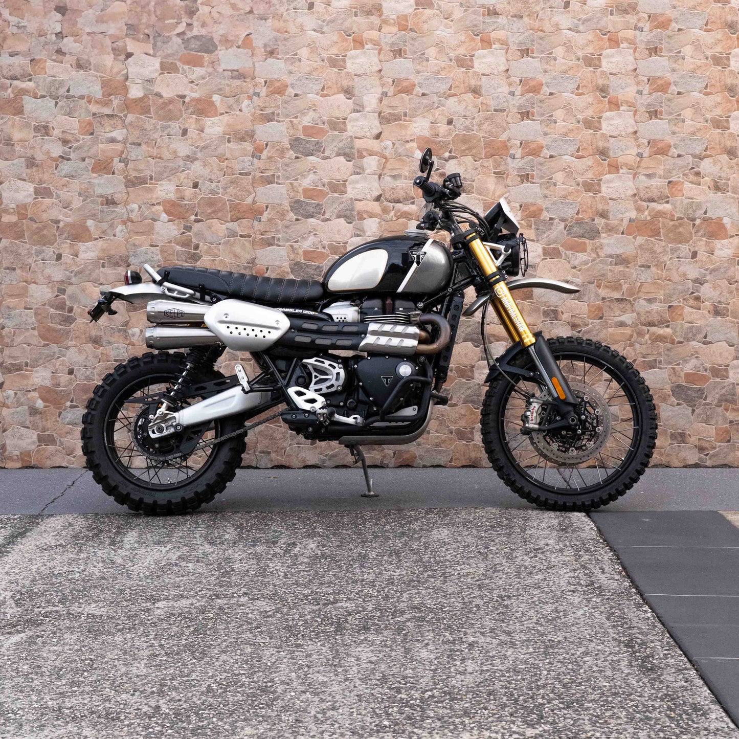 A triumph scrambler 1200 with a Kelpi Custom seat, exhaust, Rounder Mirrors and Tracker 7050 Fat bars