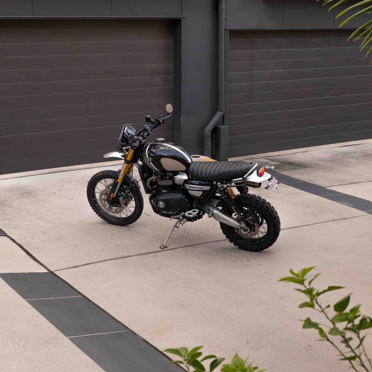 A triumph scrambler 1200 with a Kelpi Custom seat, exhaust, Rounder Mirrors and Tracker 7050 Fat bars