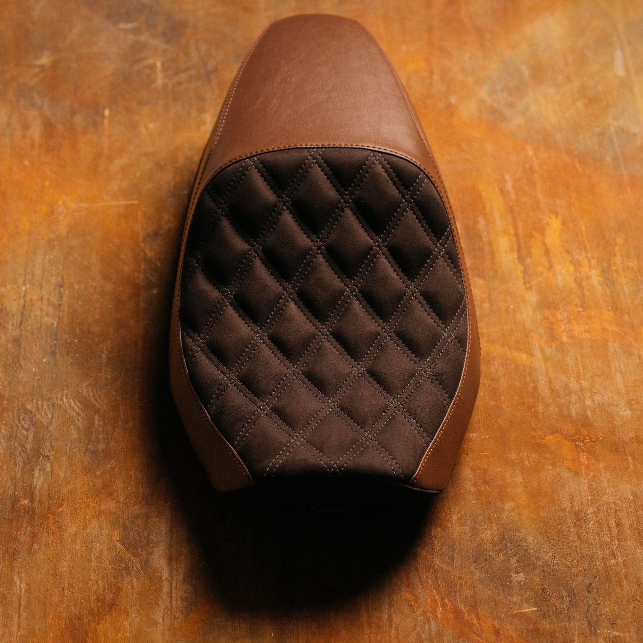 Brown quilted leather seat on a wooden surface