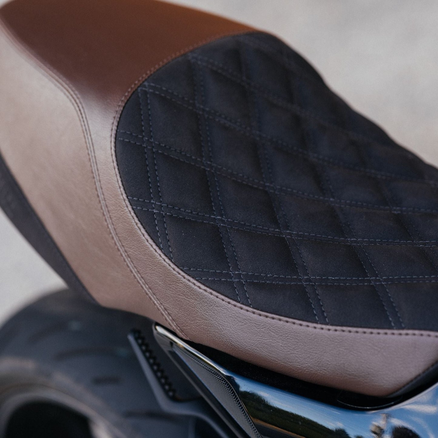 Close-up of a motorcycle seat with brown and black quilted design.