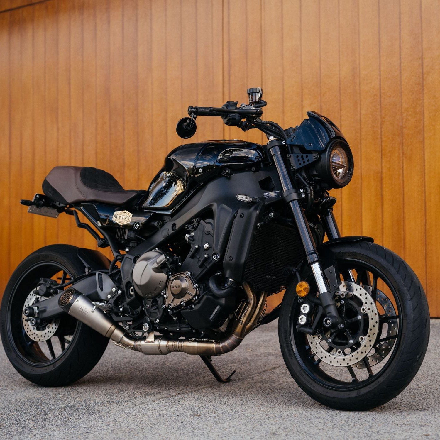 Black motorcycle parked against a wooden wall