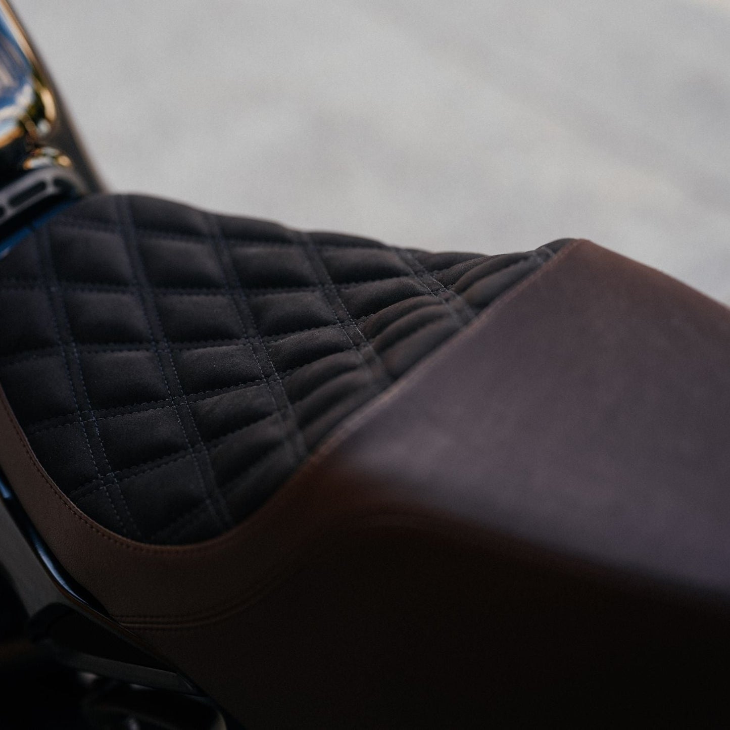 Close-up of a quilted motorcycle seat with a blurred background