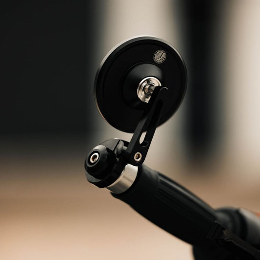 A black hindsight bar end mirror mounted on a handlebar, featuring a compact 75mm convex mirror face with a UV-treated lens.