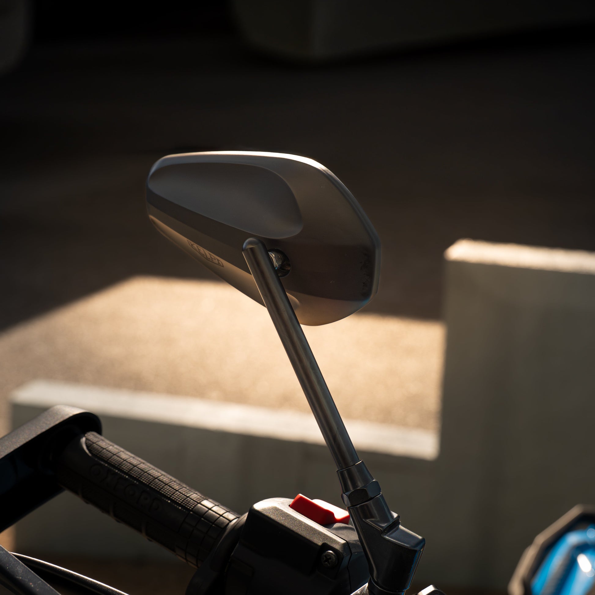 Close-up of a motorcycle mirror with blurred background