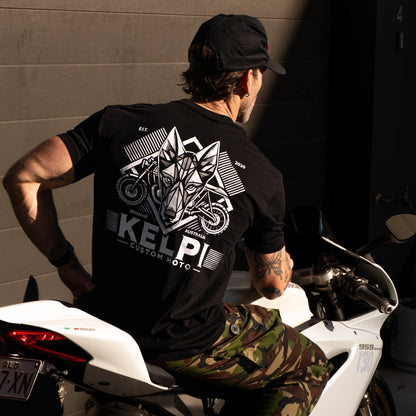 Person wearing a black t-shirt with a logo and text, sitting on a white motorcycle.
