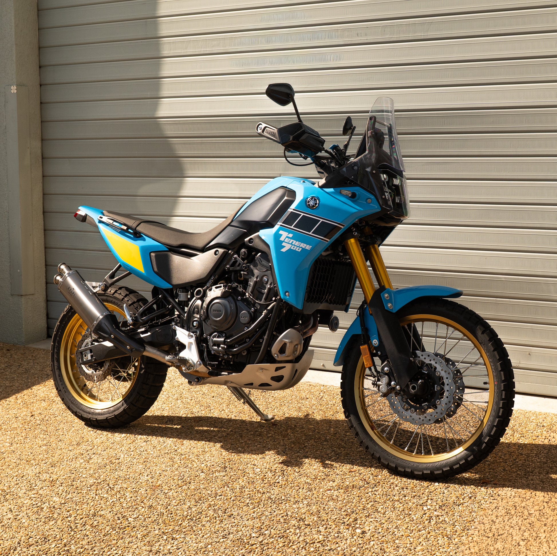 Blue motorcycle parked in front of a metallic garage door