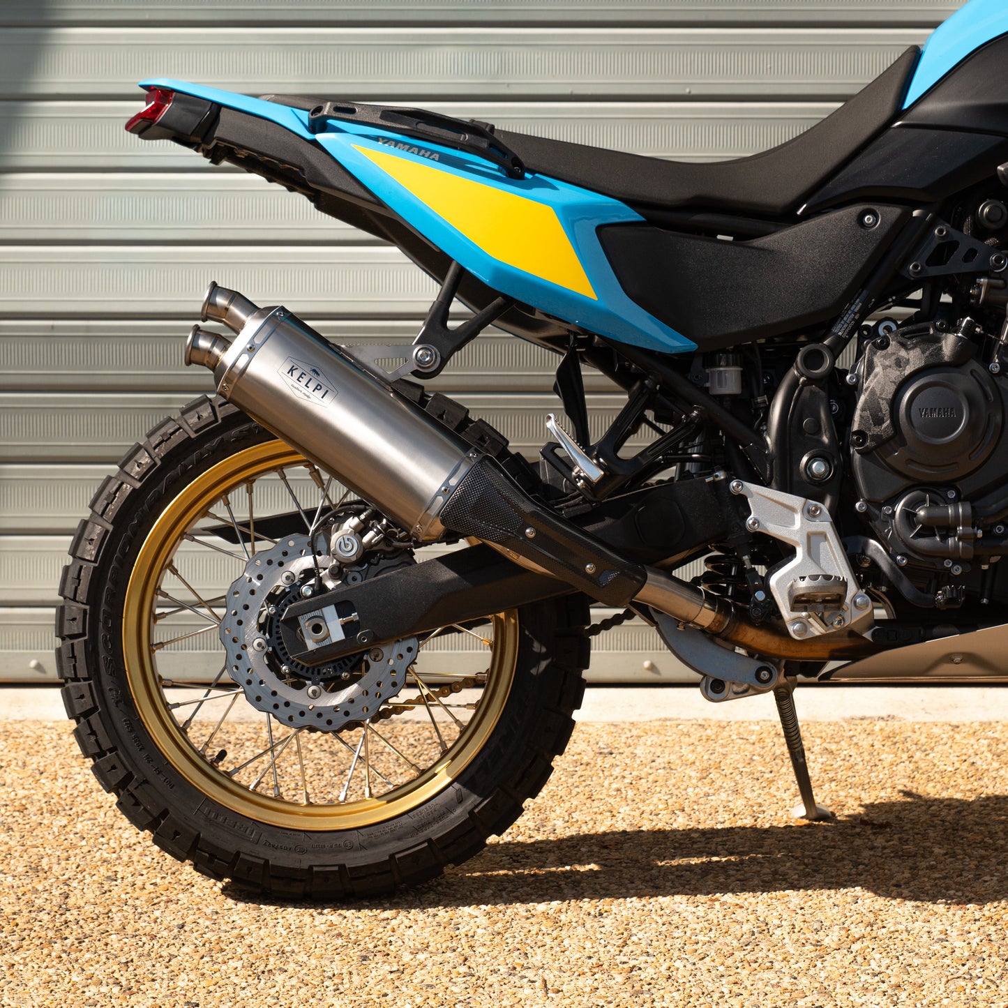 Motorcycle with blue and black design parked against a gray wall.