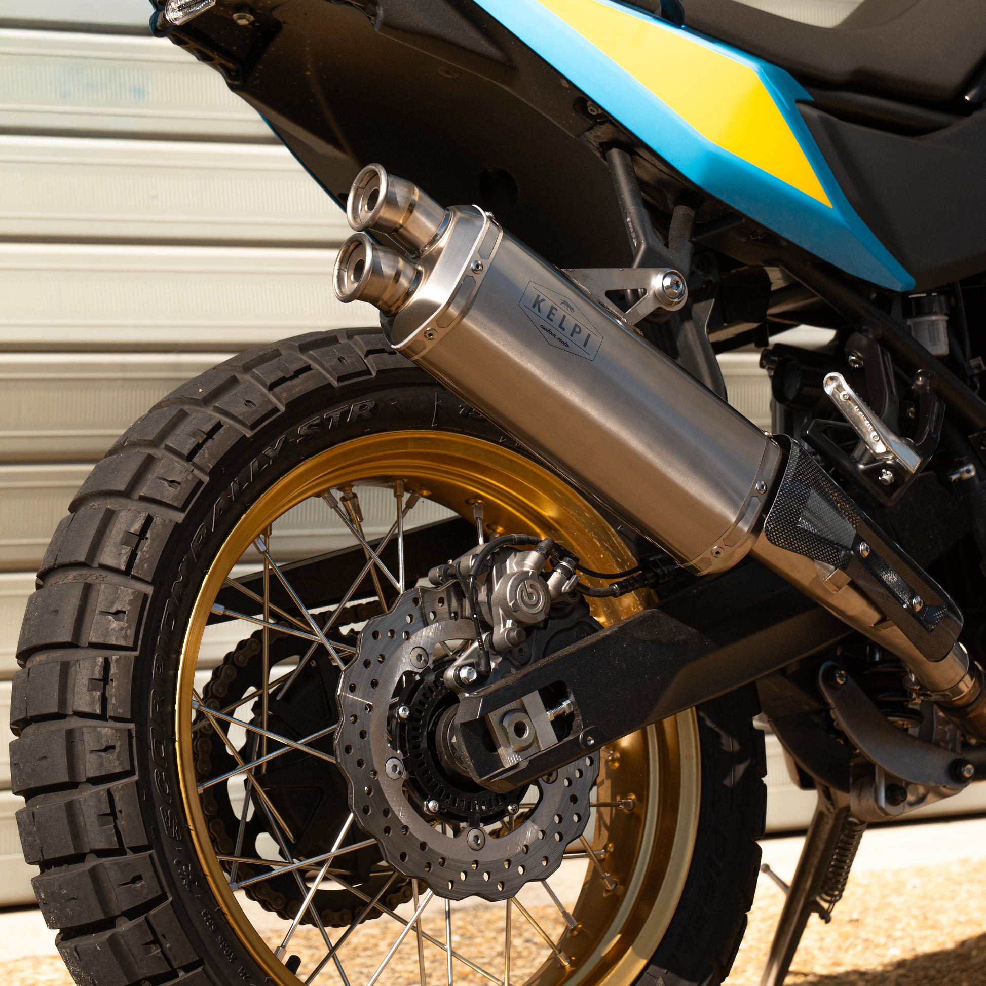 Close-up of a motorcycle's exhaust and wheel against a metallic background