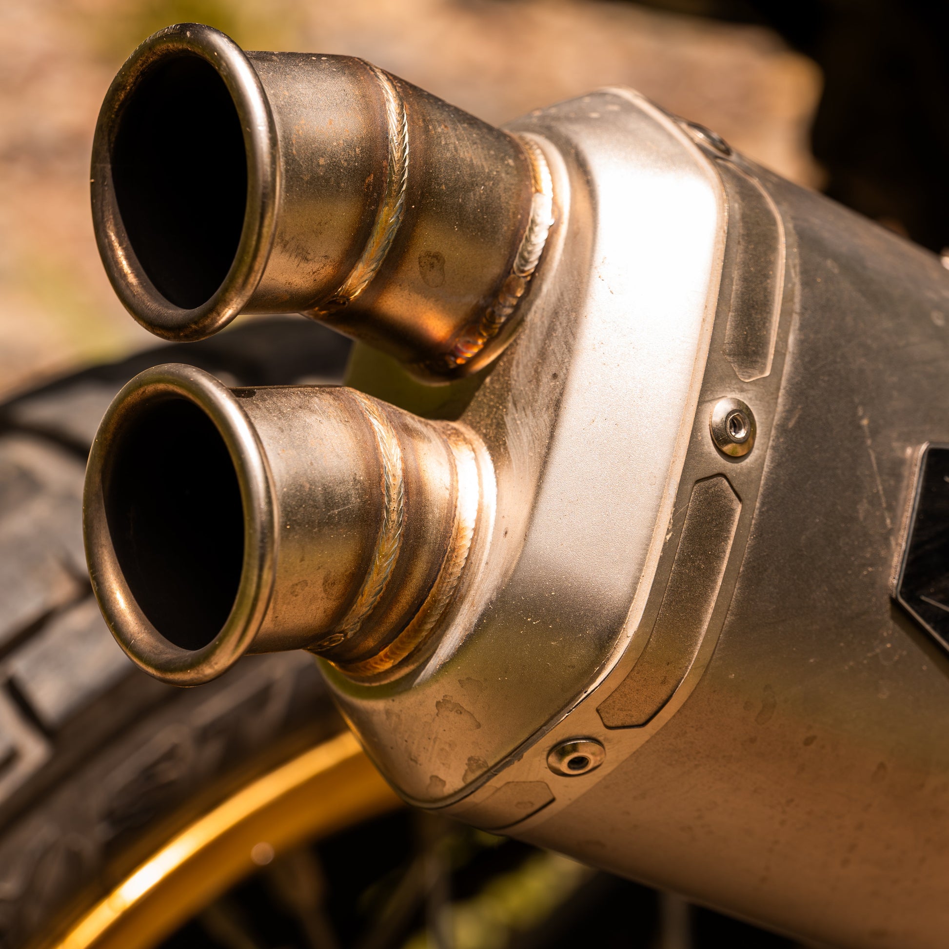 Close-up of a motorcycle exhaust with dual pipes on a blurred background