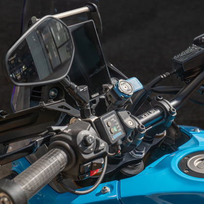 Close-up of a motorcycle handlebar with controls and mirrors on a dark background